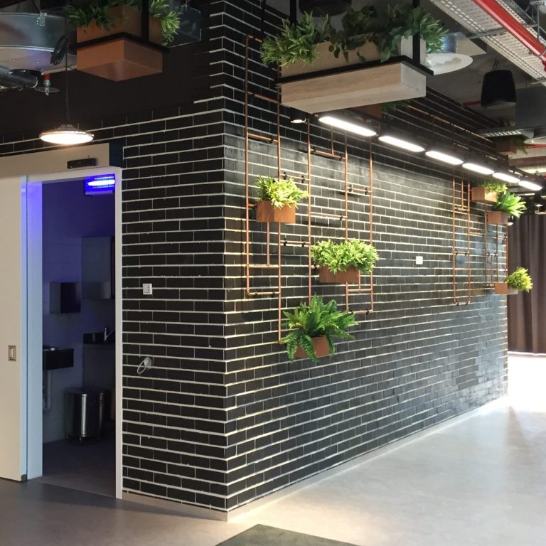 Klinkerarbeiten bei Google durch TTB München Eingang zu Google München mit schwarzen Ziegelwänden und hängenden Pflanzen.
